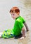 Boy sitting in shallow water