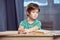 Boy sitting at table and doing homework at home