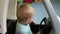 Boy sitting in a toy car. Baby closes car door and drives. Child in childrenâ€™s play center