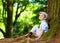 Boy sitting under an old tree, in the forest