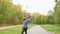 Boy skateboarder skateboarding on skateboard at pathway in summer city park. Back view boy teenager riding on long board