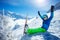 Boy skier sit in snow over mountain peaks lift hands