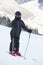 Boy skier stands on snowy slope