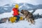 Boy sledding on winter mountain with siberian husky dog, enjoying a sledge ride in a beautiful snowy winter park. Dog