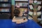 Boy sleeping in library exausted, putting head on pile of book