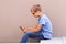 Boy with smartphone sitting on stairs outdoor. Kid wathing to screen, reading, typing, playing games