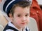 Boy with snot in his nose dressed in navy costume.