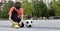 Boy soccer player tying shoelaces and soccer ball near him in town square Sports games and leisure outside concept