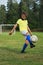 Boy soccer player in a yellow t-shirt on the soccer field juggles the ball