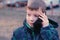 Boy speaks on a mobile phone in the Park and smiles. Front view, face close-up.