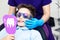 A boy in special glasses in the dentist`s chair. the doctor in sterile gloves shows him his smile in the mirror