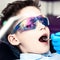 A boy in special glasses in the dentist`s chair. the doctor in sterile gloves shows him his smile in the mirror