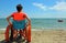 Boy on the special wheelchair with metal wheels on the beach in