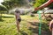 Boy splashed with water from a hose in the courtyard of the house on a hot sunny day