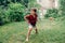 Boy splashing with gardening hose sprinkler on backyard on summer day