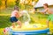 Boy splashing girl with water gun, garden swimming pool