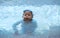 Boy split water from mouth with goggles in swimming pool in summer holiday vacation