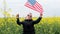 Boy standing with the american flag on the green and yellow field celebrating national independence day. 4th of July