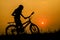 Boy and standing bicycle silhouette with sunset light. Background.