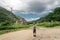 A boy standing at a crossroads in the mountains in front of an old church