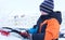 The boy standing near the car and holding a brush. The child cleans the car from snow.