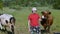 Boy standing in pasture near with cows and holding glass of fresh milk