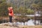 A boy standing on a rock holding a stick, admiring a view of lake, back view, Lake District, UK