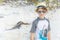 Boy standing on sand background with iguana