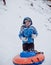 The boy standing in the snow and keeps the tubing