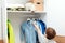 Boy standing by wardrobe with clothes. Cute boy taking school shirt to wear