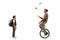 Boy standing and watching his grandfather riding a mono cycle and juggling