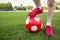 A boy stands on the football field of the stadium and holds his foot on a soccer ball. Children play football on the grass.