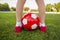 A boy stands on the football field of a stadium with a soccer ball between his legs. Children play football on the grass. Training