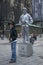 A boy stands in front of a statue street performer painted in silver in Vienna in Austria.