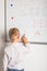 A boy stands with his back in front of a blackboard at school. Math lesson in elementary school