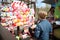 Boy stands on the opposite side of the balls and throws darts at them, trying to burst. A child plays in the park