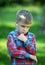 Boy stands thinking against the greenery