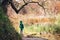 Boy stay under big tree near the pond in autumn park