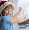 Boy is sticking a snowflake winter window in the house Christmas Eve holiday tree