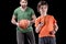 Boy with stopwatch controlling time with man holding basketball ball on black