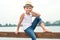 A boy in a straw hat sitting on the pier .Summer vacation on the lake