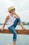 A boy in a straw hat sitting on the pier .Summer vacation on the lake