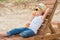 The boy in the straw hat and sunglasses lying on the wooden sun lounger on the beach and drink fresh juice.Summer vacation.