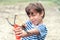 A boy in a striped T-shirt shoots a slingshot, front view