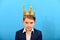 Boy in a suit and with a gold crown on his head on a blue background. domination and power over others