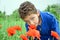 The boy on summer field stands in poppies.