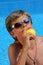 Boy with sun glasses eating an apple with pleasure