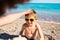 A boy in sunglasses plays on the beach