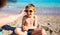 A boy in sunglasses plays on the beach