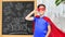 boy in super hero costume over school blackboard